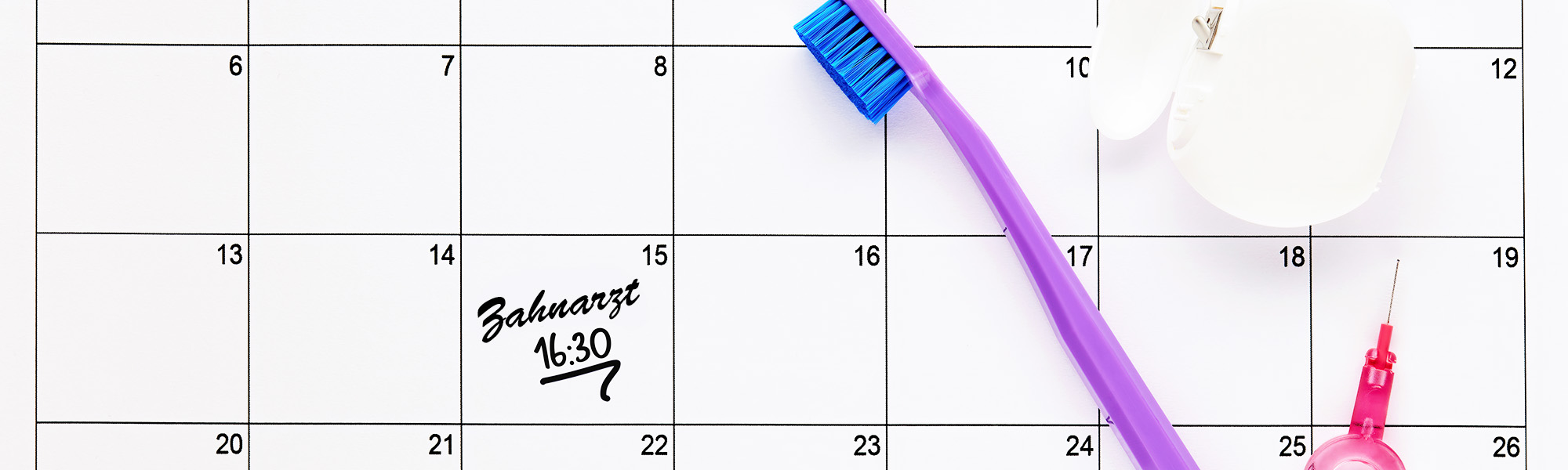 Ein Kalender, der einen Zahnarzttermin um 16:30 Uhr zeigt, mit einer Zahnbürste, die auf dem Kalender liegt.